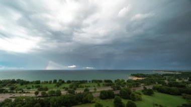 Chicago, IL - 2 Ağustos 2020: Michigan Gölü üzerinde bir yaz fırtınasının ardından gökkuşağı gökyüzünde beliriyor ve trafik Lake Shore Drive 'dan geçerken güneş parlamaya başlıyor.