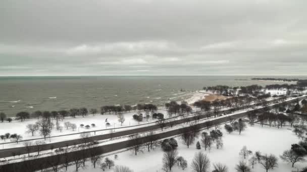 芝加哥，伊利诺伊州- 2019年1月19日：密执安州湖畔积雪覆盖覆盖覆盖，道路上的车辆驶过爱德华沃特社区的湖滨大道，裸树脱颖而出. — 图库视频影像