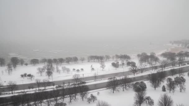 눈이 내리고 나무를 포함 한 모든 것이 하얗게 뒤덮여 있는 가운데 미 시간 호 (Lake Michigan) 의 시계탑과 시카고 북쪽의 셔어 드라이브 호수 (Lake Shore Drive) 의 교통 체증이 계속되고 있다.. — 비디오