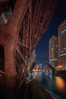 Gece Chicago Nehri 'ne bakan güzel, uzun pozlu bir fotoğraf şehir merkezindeki Wacker Yolu' ndaki döngü köprüleri şiddet ve yağmayı engellemek ve erişimi kısıtlamak için yükseliyor..