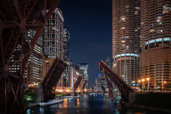 Gece Chicago Nehri 'ne bakan güzel, uzun pozlu bir fotoğraf şehir merkezindeki Wacker Yolu' ndaki döngü köprüleri şiddet ve yağmayı engellemek ve erişimi kısıtlamak için yükseliyor..
