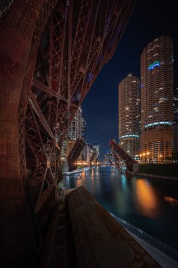 Gece Chicago Nehri 'ne bakan güzel, uzun pozlu bir fotoğraf şehir merkezindeki Wacker Yolu' ndaki döngü köprüleri şiddet ve yağmayı engellemek ve erişimi kısıtlamak için yükseliyor..