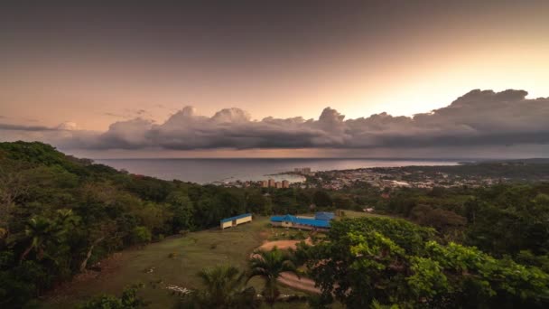 Luchtfoto panning zonsopgang timelapse van Ocho Rios van een heuvel met Caribische zee, baai en gebouwen beneden en oranje en roze wolken boven op het tropische eiland Jamaica een populaire reisbestemming. — Stockvideo