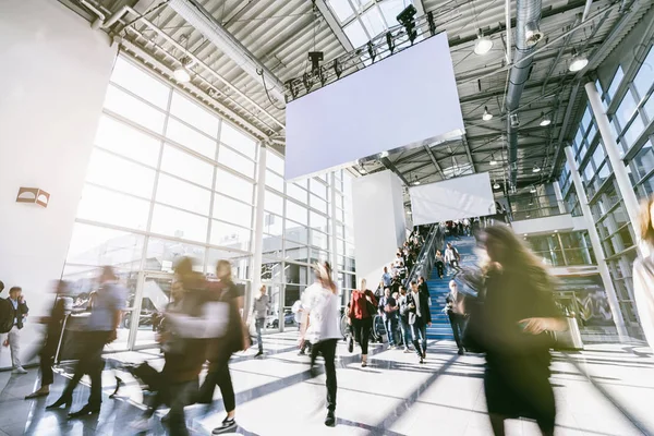 Anonymous blurred business people rushing in a hall of a trade f