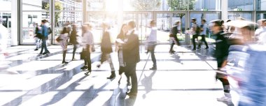 Bir ticaret fuarında yürüyen bir sürü isimsiz insan.