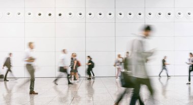 Anonim insanlardan oluşan büyük bir kalabalık modern bir salonda yürüyor.