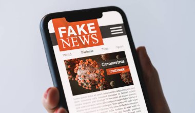 Online Corona Fake news on a mobile phone. Close up of woman reading Fake news or articles about covid-19 in a smartphone screen application. Hand holding smart device. Mockup. COVID19 nCov Outbreak.