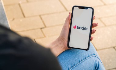 BERLİN, ALMANY AĞUSTOS 2019: oturum açmak için Tinder uygulamasının logosu olan iPhone X 'leri tutan kadın. Tinder, internetteki romantik randevular için çok platformlu insanların yer belirleme uygulaması. Çok ünlüdür..