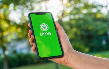 BERLİN, ALMANY AĞUSTOS 2019: Bir e-scooter kiralamak için akıllı telefonunda LIME uygulamasının logosunun olduğu iPhone X 'leri tutan kadın. Lime kiralık bir elektrikli scooter şirketi. Hızlı ve kolay bir yolculuk.