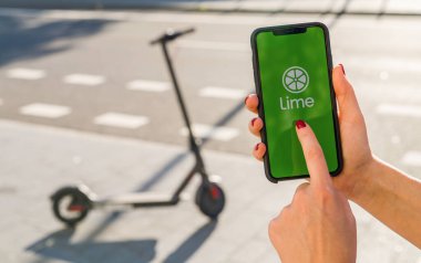 BERLİN, ALMANY AĞUSTOS 2019: Bir e-scooter kiralamak için akıllı telefonunda LIME uygulamasının logosunun olduğu iPhone X 'leri tutan kadın. Lime kiralık bir elektrikli scooter şirketi. Hızlı ve kolay bir yolculuk.