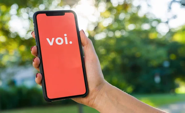 2019年8月 女性手持带有Voi应用标识的Iphone 展示在智能手机上 以租用一部电子摩托车 Voi是一家租来的电动车公司 简便的旅行方式 — 图库照片
