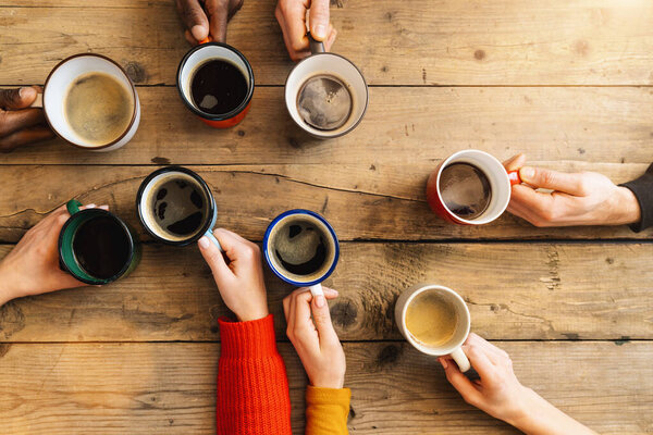 Друзья группы пить кофе и капучино в баре или ресторане - Люди руки приветствия и тосты на верхней точки зрения - завтрак вместе концепции с белыми и черными мужчинами и женщинами

