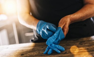 İş yerinde Coronavirus Corona virüsü virüsü kapmasını önlemek için lateks eldiven takan barmen ya da çalışan..