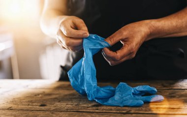 Corona COVID-19 ve SARS enfeksiyonunu önlemek için iş yerinde tıbbi lateks eldiven takan barmen veya çalışan.
