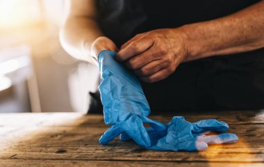 Corona COVID-19 ve SARS enfeksiyonunu önlemek için iş yerinde tıbbi lateks eldiven takan barmen veya çalışan.
