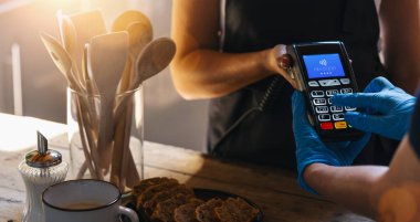 Tıbbi lateks koruyucu eldivenli bir kadın bir kafedeki ödeme terminalinde PIN koduna giriyor. Coronavirus veya COVID-19 için koruma. 