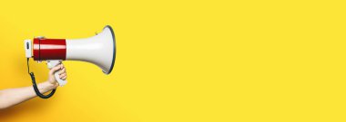 Boş sarı arkaplan önünde bir megafonla el ele, afiş boyutu, bireysel metin alanınız için telif alanı.