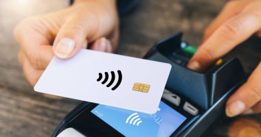 Temassız ödeme konsepti, NFC teknolojisinin yanında kredi kartı tutan kadın müşteri, müşteriler restorandaki RFID makinesinde işlem ödeme faturası yapıyor, manzarayı kapatıyorlar.
