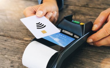 Temassız ödeme konsepti, NFC teknolojisinin yanında kredi kartı tutan kadın müşteri, restorandaki ya da mağazadaki RFID makinesinde işlem ödeme faturası yapan müşteri, manzarayı kapat