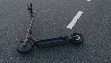 Elektrikli scooter veya e-scooter kazadan sonra yolda yatar, kentsel taşıma konsepti görüntüsü 