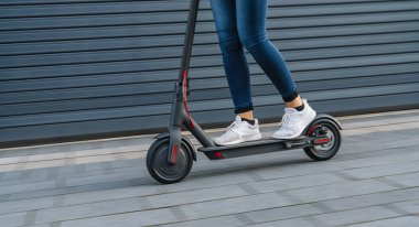 Şehir manzarasında, hareket bulanıklığında siyah elektrikli scooter kullanan bir kadın.