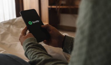 BERLİN, ALMANY AĞUSTOS 2019: Yatakta iPhone X açan bir kadın spotify uygulaması açıyor, Spotify yasal müzik sunan bir müzik servisidir.