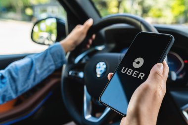 BERLİN, ALMANYA HAZİRAN 2019: Uber sürücüsü akıllı telefonu arabada tutuyor. Uber, internet üzerinden ulaşım hizmeti sunan bir Amerikan şirketidir. İllüstrasyon Editörü.