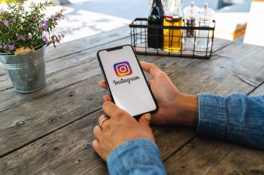 BERLİN, ALMANY HAZİRAN 2019: Bir restoranda Instagram uygulaması logosu olan iPhone X 'leri tutan kadın. Instagram en büyük ve en popüler sosyal ağdır..