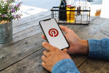 BERLİN, ALMANY HAZİRAN 2019: Bir restoranda Pinterest uygulamasının logosu olan iPhone X 'leri tutan kadın. Pinterest, insanların ilginç şeylerini iğnelemesini sağlayan çevrimiçi bir pinboard..