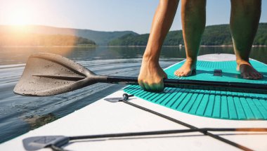 Kürek tahtasındaki kişi ayağa kalkmaya çalışır.