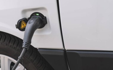 Elektrikli araba için güç kaynağı dolu. Elektrikli araba şarj istasyonu. Şarj edilen bir elektrikli arabaya takılan güç kaynağını kapatın..