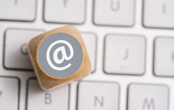 Email at icon on a wood cube on a keyboard. Contact and Communication Methods concept image