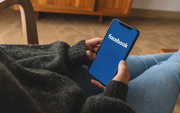 2019年8月 女性手持带有Facebook应用标识的Iphone Xs进入一个活生生的Roo Facebook是Mark Zuckerber于2004年2月创立的在线社交网络服务 — 图库照片