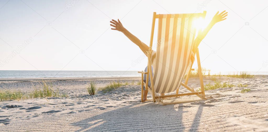 happy young woman sitting on beach chair on beach at summer, copyspace for your individual text, banner size