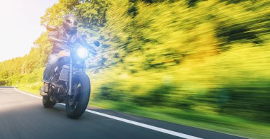 Modern scrambler motosiklet sürme orman yolu üzerinde. Bir motosiklet Tur yolculuğa boş yol sürüş eğleniyor. Gerçek dinamik hareket bulanıklığı atış. Boşaltmak için bireysel metin.
