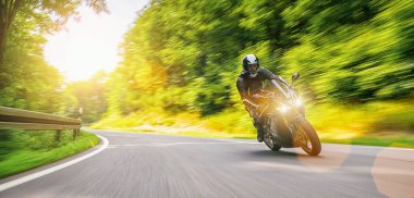 Orman yolunda hızlı giden bir motosiklet. Boş yolda araba kullanırken eğleniyorum..