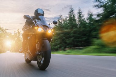Gün batımında ormanda motosiklet sürmek. Motosiklet gezisinde boş yolda araba kullanmak. bireysel metniniz için kopyalama alanı.