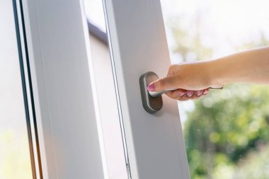 Kadın kolu beyaz plastik pencereyi açıyor