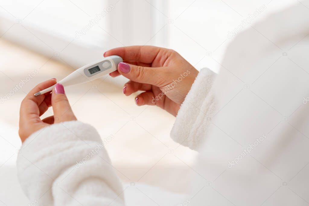 female hands holding a digital thermometer with high temperature