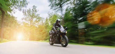 Orman yolunda motosiklet sürmek. Motosiklet gezisinde boş yolda araba kullanmak. bireysel metniniz için kopyalama alanı.