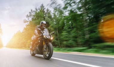 Orman yolunda motosiklet sürerken. Gün batımında motosiklet turunda boş yolda araba kullanmak. bireysel metniniz için kopyalama alanı.