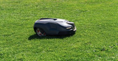 Robotik çim biçme makinesi bahçedeki çimleri biçiyor.