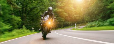 Orman yolunda motosiklet sürmek. Motosiklet gezisinde boş yolda araba kullanmak. bireysel metniniz için kopyalama alanı.