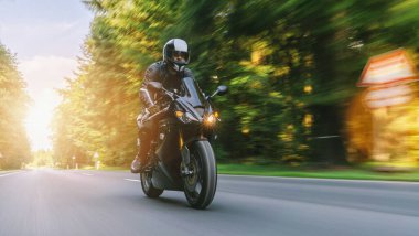 Yazın orman yolunda motosiklet sürmek. Bir motosiklet gezisinde boş yolda araba kullanmak. bireysel metniniz için kopyalama alanı.