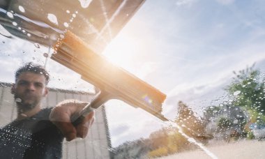 İşçi adam cam sileceği ile araba yıkıyor. Araba yıkama konsepti. bireysel metniniz için kopyalama alanı.