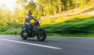 Gün batımında ormanda motosiklet sürmek. Motosiklet turunda boş bir yolda araba sürerken eğleniyorum. bireysel metniniz için kopyalama alanı.