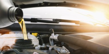 Araba motoruna motor yağı dökülüyor, arabaya yağ değişimi sırasında taze yağ dökülüyor..