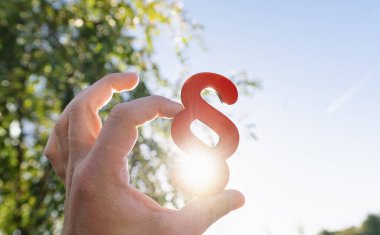 Kırmızı paragraf sembolünü tutan kişinin yakın plan fotoğrafı.