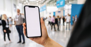 Ticaret fuarında beyaz ekranlı siyah cep telefonlu iş kadını eli bireysel metnin için telif alanı.