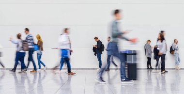 Bir ticaret fuarında ya da havaalanında isimsiz bir iş adamı kalabalığı vites kolundan yürüyor